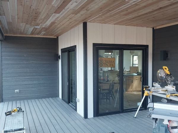 Covered porch with cedar ceiling, composite decking and black sliding doors