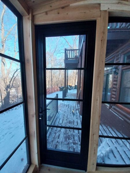 View out through the four-season room door to a snowy deck