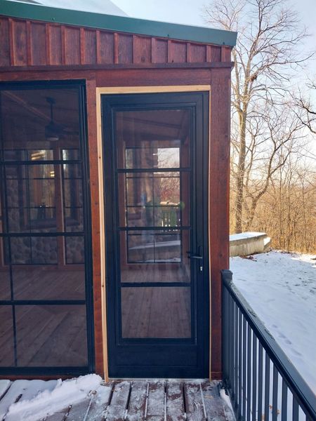 Black full-glass door and cedar trim on a four-season room in winter