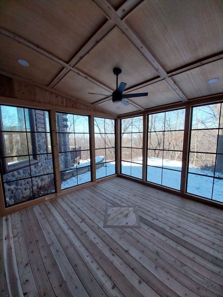 Four-season room interior with cedar floor, coffered wood ceiling and black-framed windows