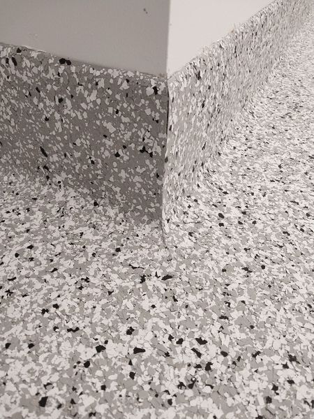 Speckled seamless floor finish carried up the wall as a cove base