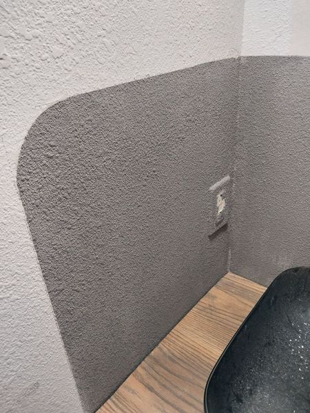Bathroom wall finished in gray microcement with a curved top edge