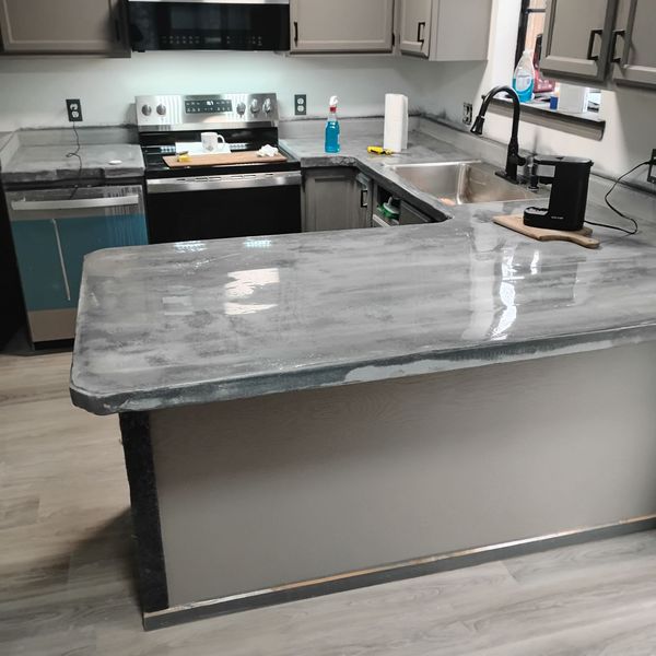 Kitchen peninsula and perimeter countertops finished in gray microcement with a polished sheen